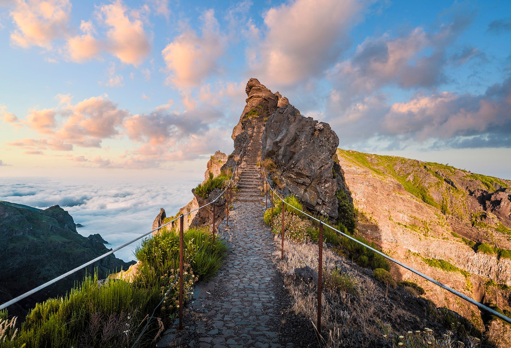 A staircase leading up to a rocky cliff above the clouds on Pico do Areeiro on the island of Madeira