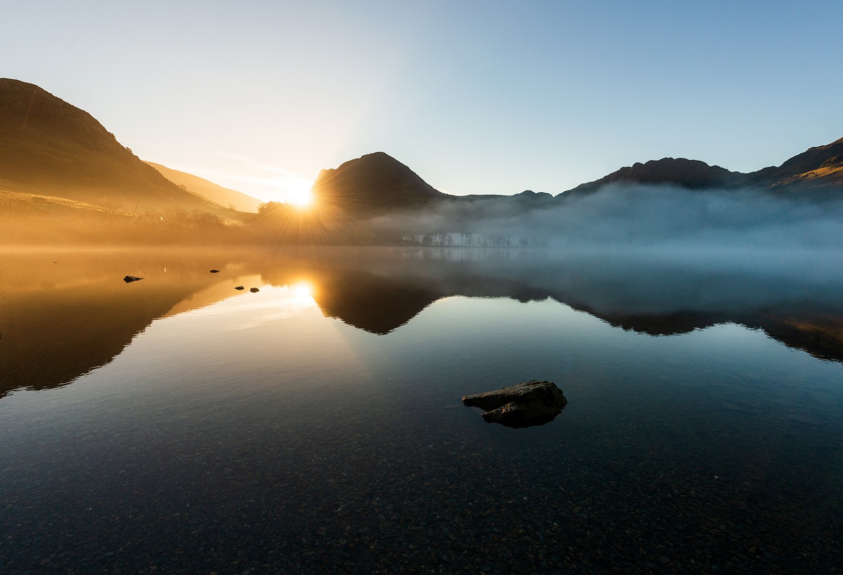 Benefits A scenic photo of a hills surrounding a lagoon on a sunset