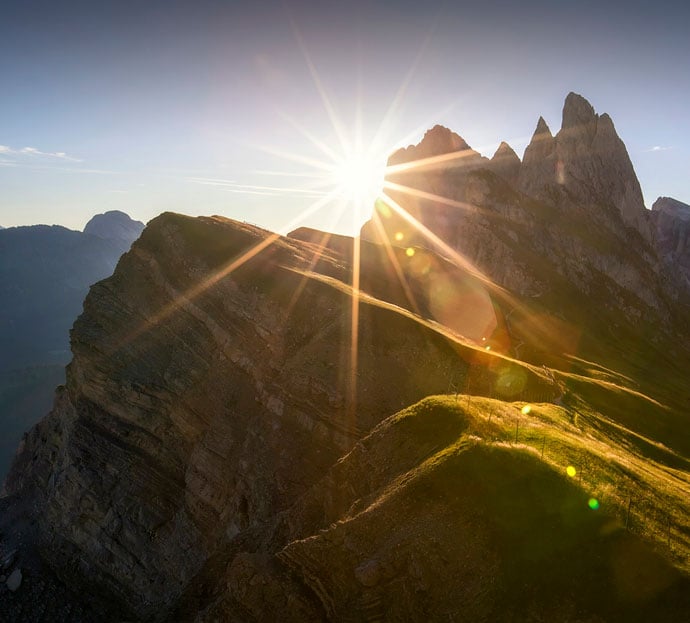 The sun peering out between a gap in a steep hill range