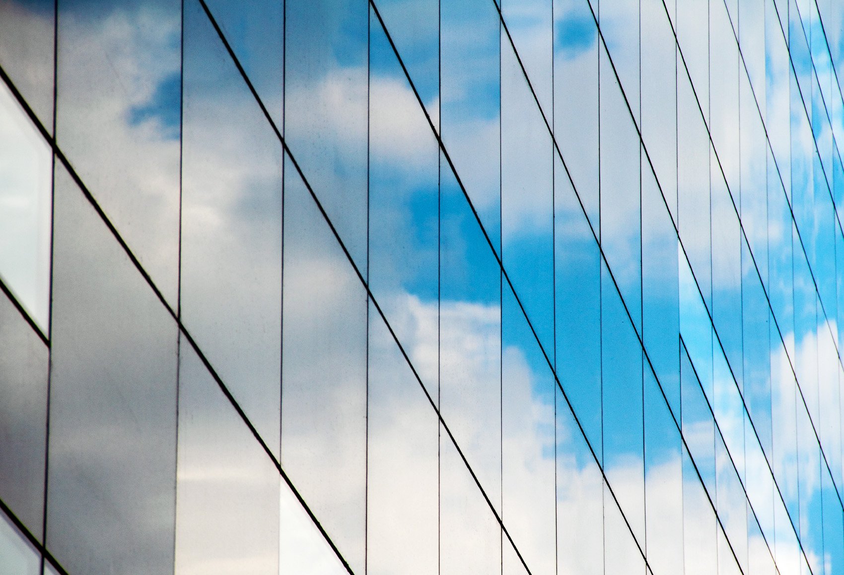 A reflection of clouds and sky in a mirrored glass building