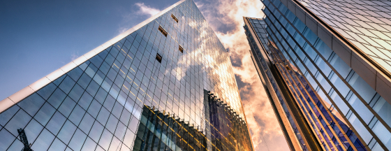 Looking up in between two clear windowed skyscrapers