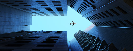 low-angle photograph looking up at skyscrapers with an airplane flying overhead