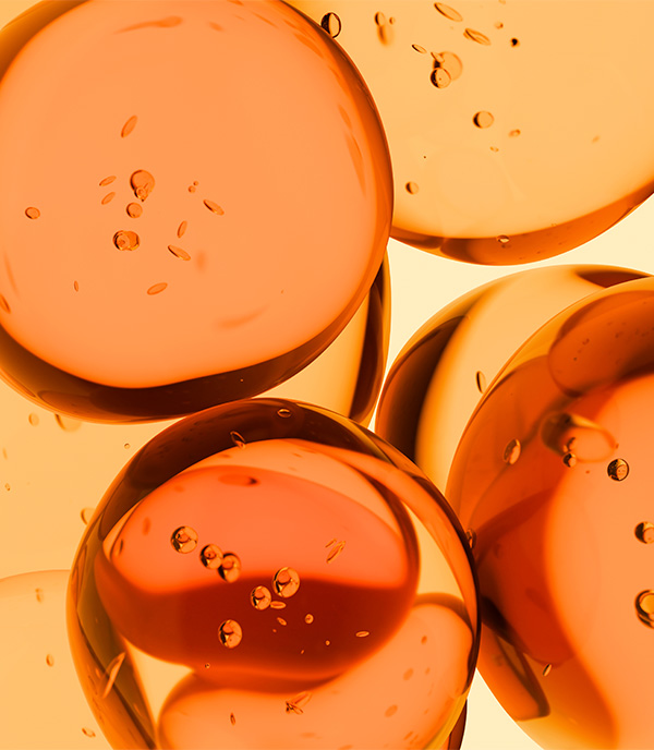 Abstract close-up of translucent orange spheres with tiny bubbles suspended inside against a golden background.