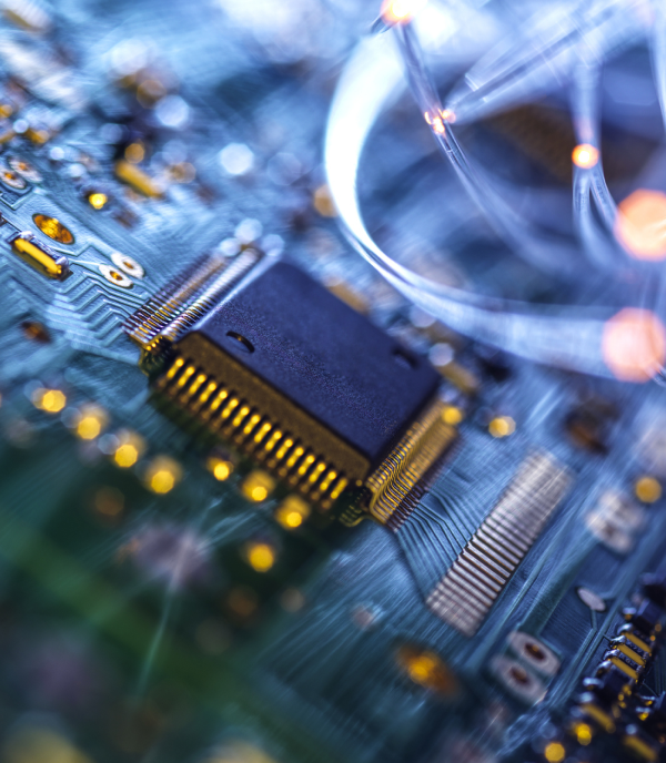 Close-up of a microchip on a blue circuit board with gold connections and glowing fiber-optic strands.