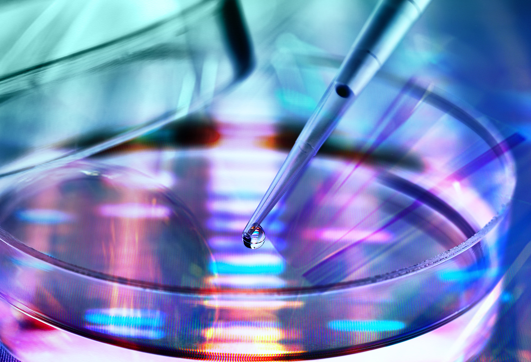 Close-up of a laboratory pipette releasing a droplet into a petri dish, overlaid with colorful DNA sequencing patterns, representing biotechnology and life sciences innovation.