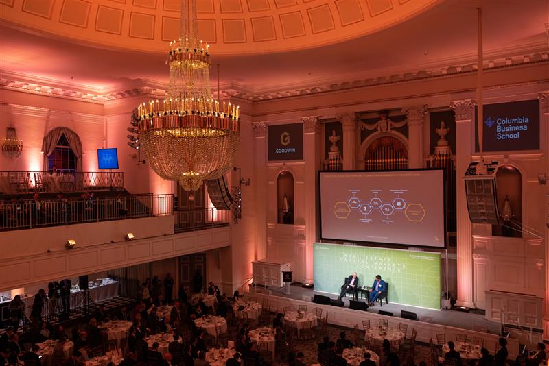 Speaker presenting with a slideshow at the Goodwin real estate capital markets conference.