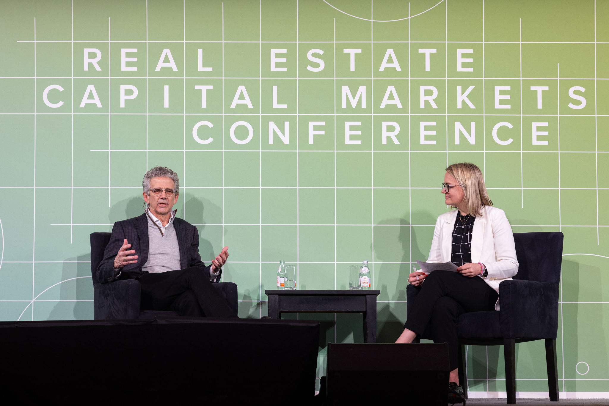 Audience member asking a question with a microphone during a panel at the Goodwin and Columbia Business School Real Estate Capital Markets Conference.