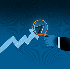 A person holding up a yellow magnifying glass on the end arrow of a trend line