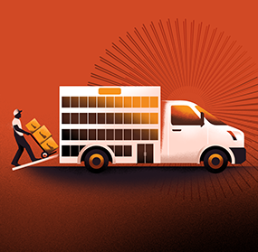 A person loading boxes on a hand truck into a white van truck with square decorations on the exterior