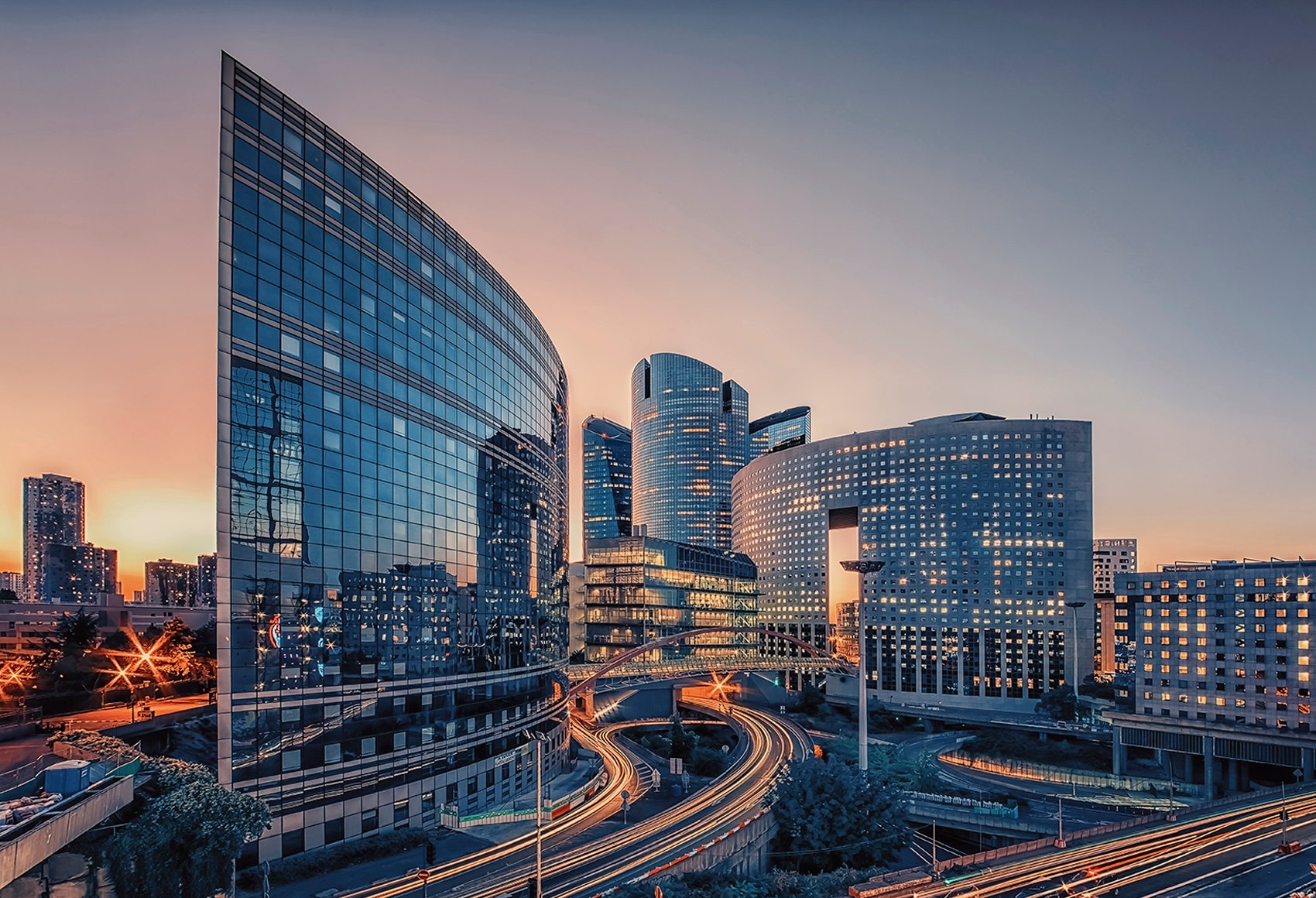 A shot of a few curved glass Highrise buildings during a sunset