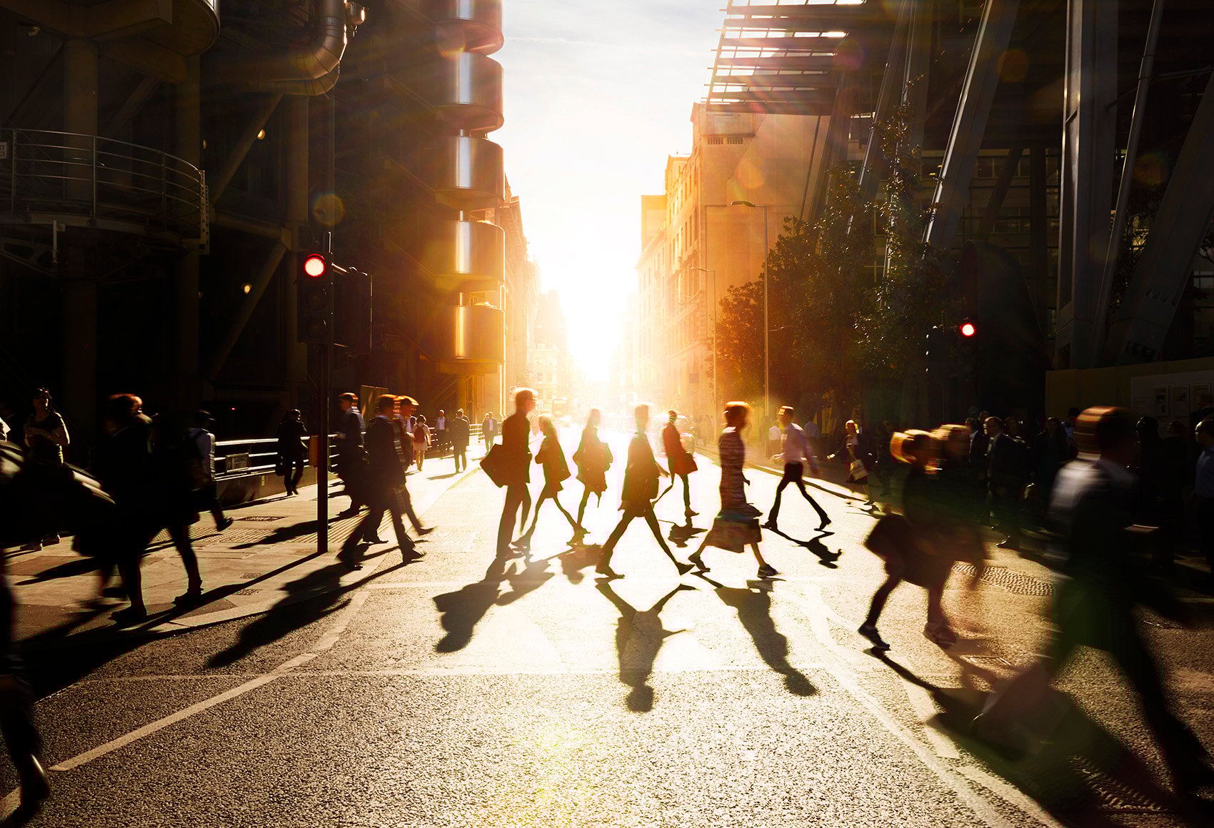 A large group of people crossing a street at traffic lights in a city