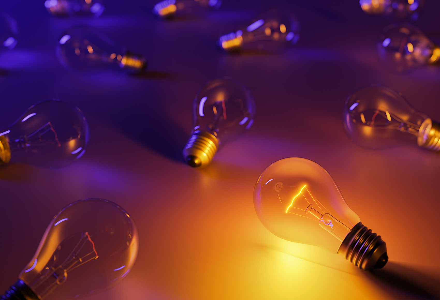 A cluster of loose light bulbs laid out on a flat surface, it is dark with only one switched on