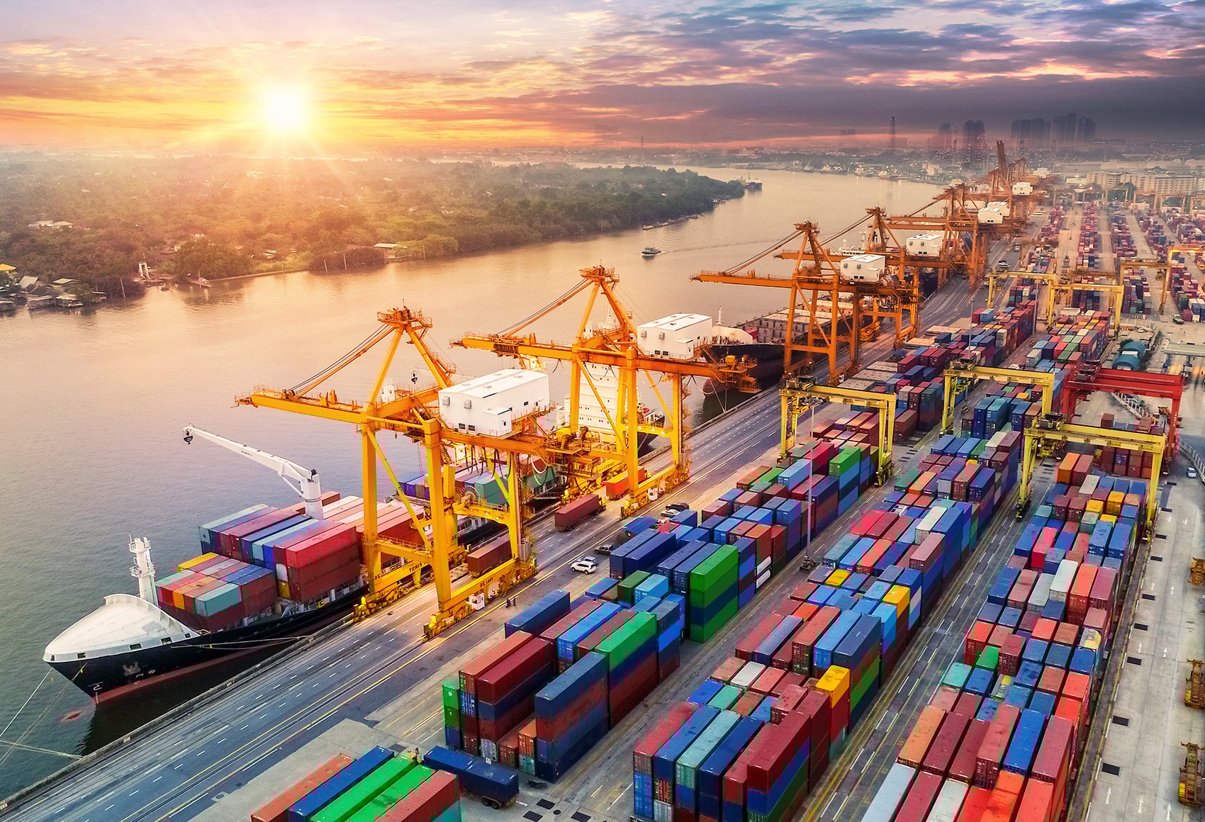 A shipment storage facility filled with containers and yellow cranes