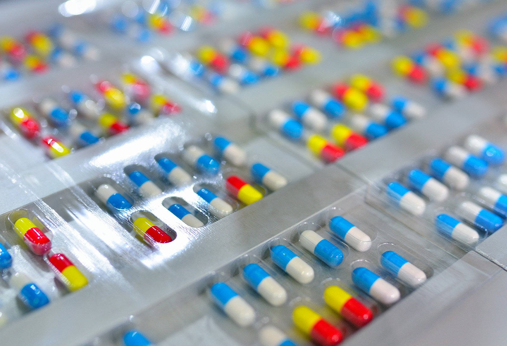 An image of many blue and yellow capsules neatly arranged in rows on trays.